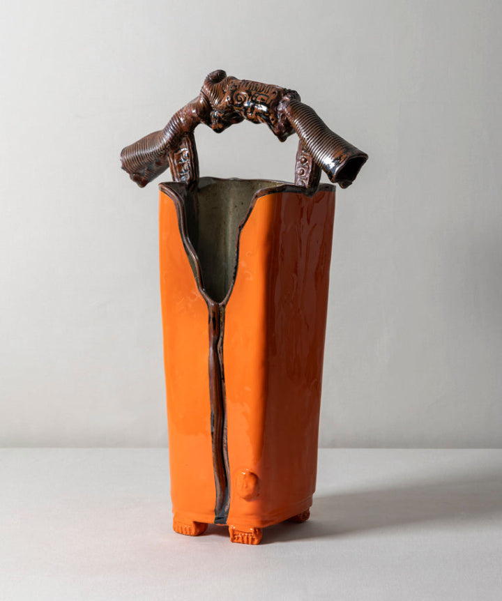 A tall, architectural ceramic vessel featuring a museum grade sculptural handle. Sharp, organic, tailored, and deliberate.