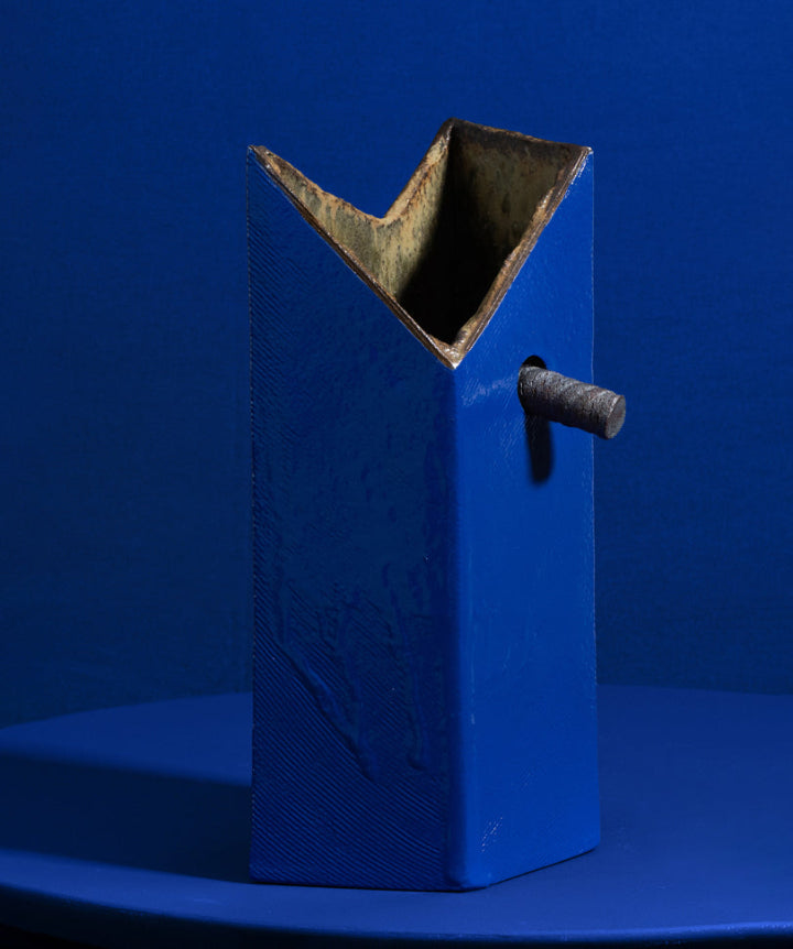 An edgy and truly unique vase made of ceramic drip glaze. The asymmetrical, textured exterior and smooth interior are separated by a removable ceramic pole running through its center.