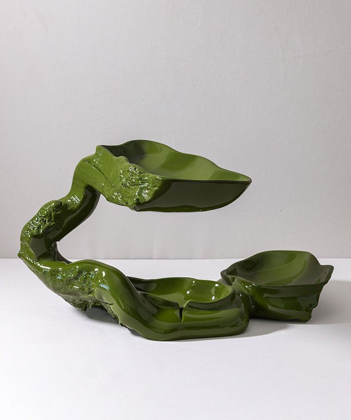 A glossy olive green ceramic sculptural dish with three integrated bowls, photographed on a white surface against a light gray background.