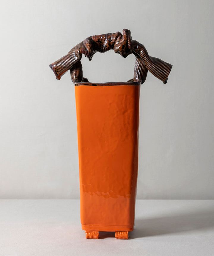 A tall, architectural ceramic vessel featuring a museum grade sculptural handle. Sharp, organic, tailored, and deliberate. 