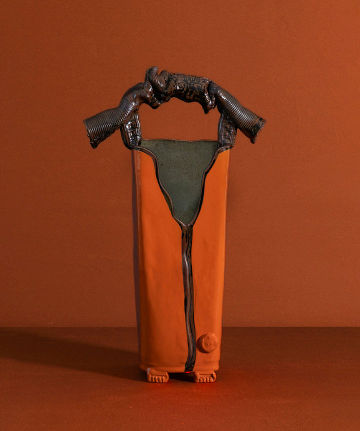 A tall, architectural ceramic vessel featuring a museum grade sculptural handle. Sharp, organic, tailored, and deliberate.